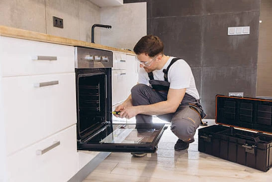 Technician repairing an open built-in oven
