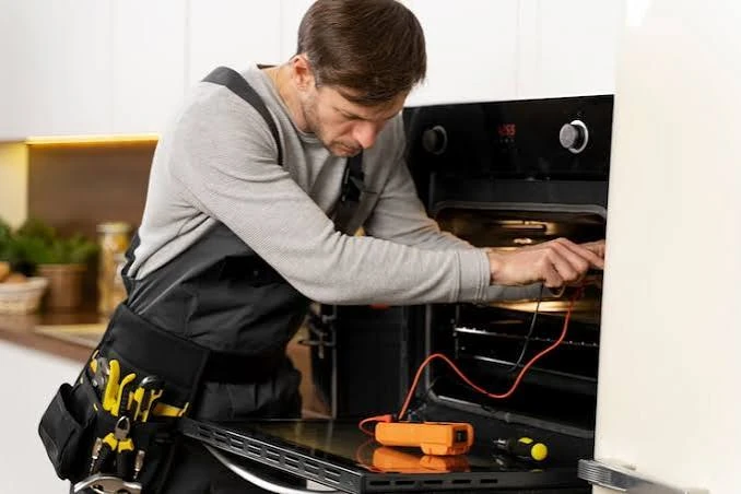 Technician using a multimeter to diagnose a built-in oven
